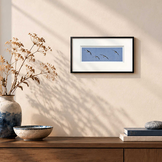 Oyster Catchers in Flight handmade print in white double mount and black frame on wall in room set.