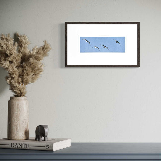 Oyster Catchers in Flight handmade print in white double mount and black frame on wall in room set.