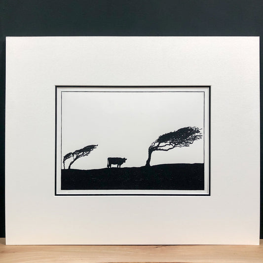 Original handmade woodblock tree print of windswept hawthorns and cow in black ink on cream paper, fourth print in a series of four, mounted with wide cream mount and black inner mount.