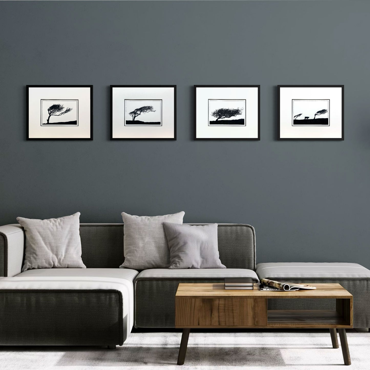 Four original handmade woodblock prints of windswept hawthorn trees in black frames displayed on a dark neutral wall, forming a quietly dramatic monochrome landscape series.